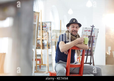Portrait smiling, confident male artist drinking coffee in art class studio Stock Photo