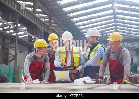 Male foreman, engineers and workers meeting in factory Stock Photo