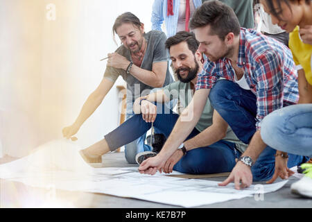 Artists discussing sketches on floor in art class studio Stock Photo