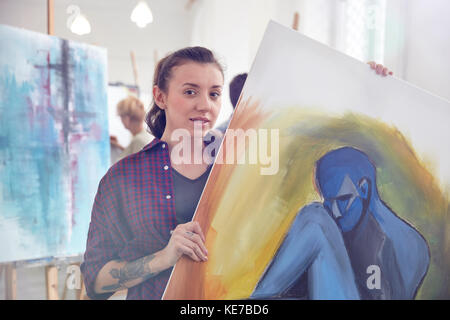 Portrait female artist holding, showing painting in art class studio Stock Photo