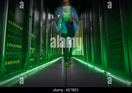 IT technician walking in dark, glowing server room Stock Photo