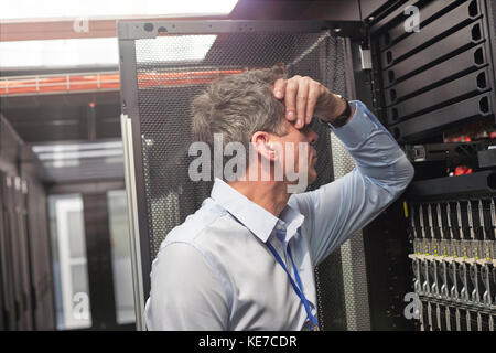 Frustrated IT technician at panel in server room Stock Photo