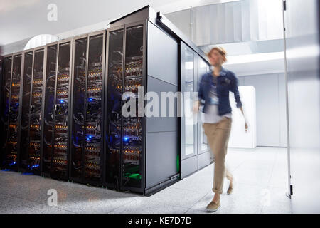 Female IT technician walking in server room Stock Photo