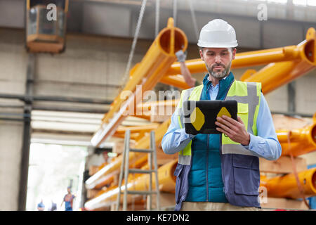 Serious male engineer using digital tablet in factory Stock Photo