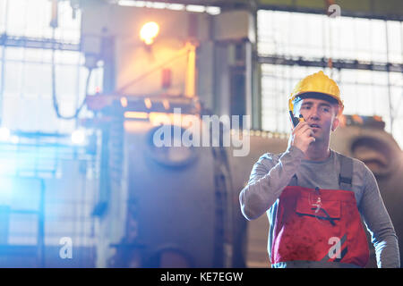 Male worker talking on walkie-talkie in steel factory Stock Photo