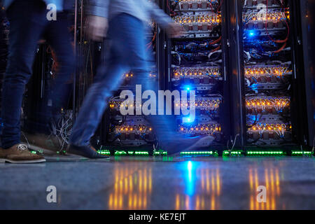 IT technicians walking in dark server room Stock Photo