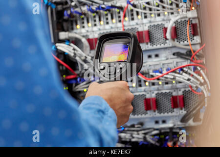 IT technician using diagnostic thermal imagining camera equipment in server room Stock Photo