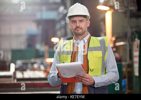 Portrait confident male foreman with clipboard in factory Stock Photo
