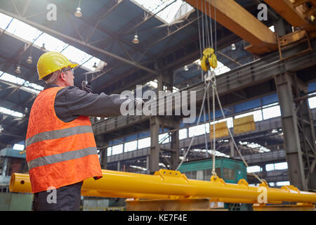 Male worker guiding hydraulic crane in factory Stock Photo