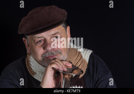 Nice portrait of retired smiling senior man taking an old trumpet in darkness Stock Photo
