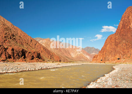 A River Snakes Through Colourful Mountains In The Dry Andes, Two Road Tunnels Are Visible; Mendoza, Argentina Stock Photo