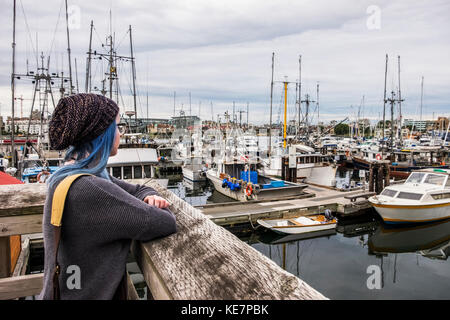 Young Woman Looks Out Over Fisherman's Wharf; Victoria, British Columbia, Canada Stock Photo