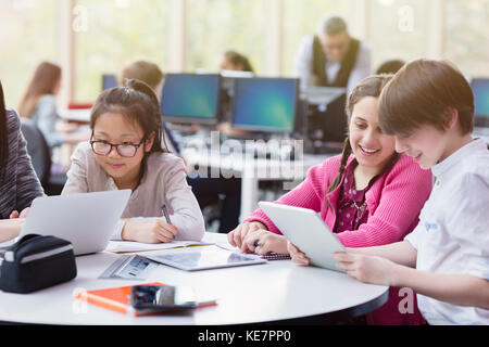Students using digital tablet and laptop in library Stock Photo