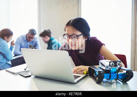 Focused girl student programming robotics at laptop in classroom Stock Photo