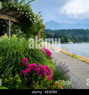Flowers and lush plants in a colourful landscaped area along a promenade on Slocan Lake; New Denver, British Columbia, Canada