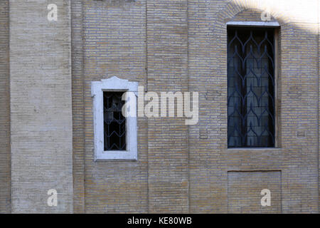 two different sized windows set in a brick wall made from very small bricks  of a pale colour. Stock Photo