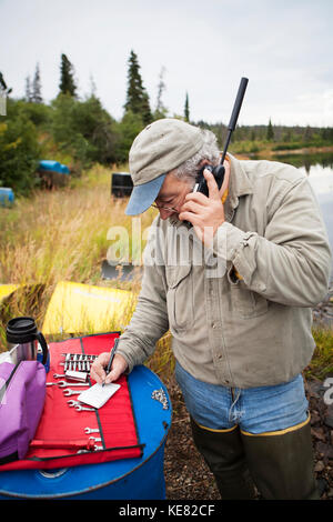 Person On A Satellite Phone During A Remote Moose Hunt, Lake Iliamna, Southwest Alaska, USA Stock Photo