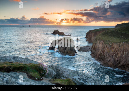 Sunset over Enys Dodnan and the Armed Knight rock formations in the sea at Land's End on the rugged Cornwall coast
