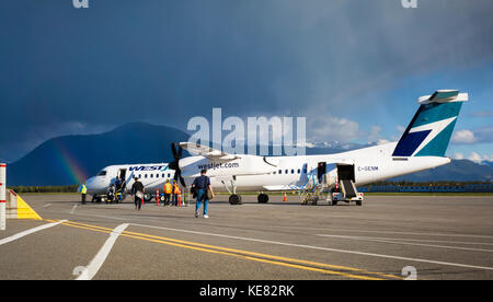 Rainbow Over The Terrace Kitimat Airport As Passengers Load A Plane On The Tarmac; Terrace, British Columbia, Canada Stock Photo