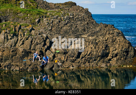 A Father And Son Fishing In The Tide Pools Along The Coast Of Northern Ireland; Ireland Stock Photo