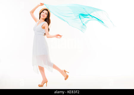 Side view of young smiling woman in summer dress and hat posing holding fluttering cloth Stock Photo