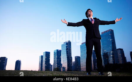 Businessman standing opening his arms in city at night Stock Photo