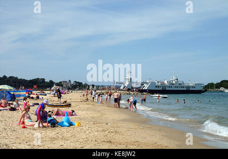 Families on Studland bay beach, and Sandbanks ferry in the background, Dorset, England Stock Photo