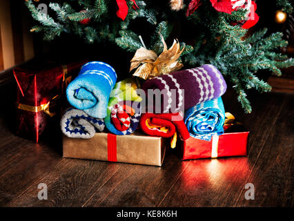Christmas gifts and woolen eco-scarves next to the Christmas tree. Christmas presents background. Scarves made of Dundaga wool. Stock Photo