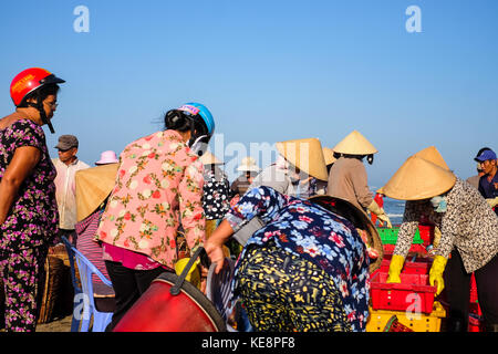 Ba Ria-Vung Tau, Viet Nam. Local people working at marketplace, woman is selective fish and man is carry basket fresh fish from ship on the beach Stock Photo