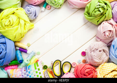 Accessories for sewing lie on a white background. Measuring tape, thread, fabric, needle bar and needles for sewing. Stock Photo