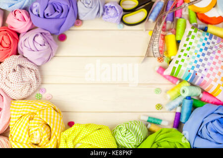 Accessories for sewing lie on a white background. Measuring tape, thread, fabric, needle bar and needles for sewing. Stock Photo