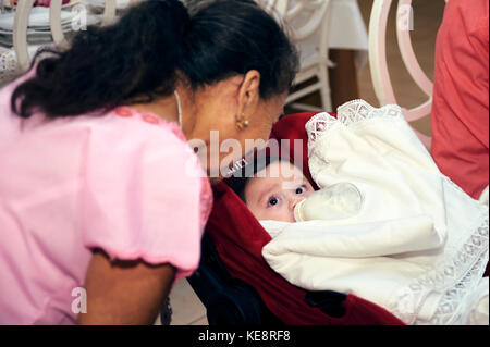 Grandmother talking to baby on stroller while feeding him Stock Photo