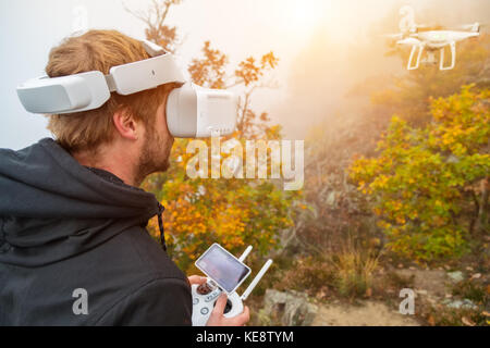 Young man handling drone, using virtual reality glasses. New technology and trends in photo and video recording. Stock Photo