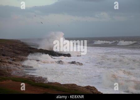 High winds driving in a stormy sea against the rocks resulting in huge waves and wind driven spray flying high. Stock Photo