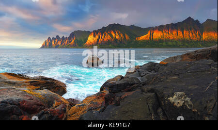 Evening norway seascape. Dragon's teeth rocks in sunlight on colorful sky background. Stock Photo