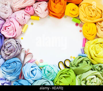 Accessories for sewing lie on a white background. Measuring tape, thread, fabric and needles for sewing. Color fabric. Stock Photo