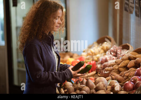 Woman picking fresh produce from a vegetable stall at a farm market grocery store Canada Stock Photo