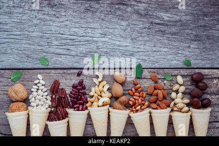 Concept for homemade various nuts ice cream. Mixed nuts in waffle cones on shabby wooden background.top view Stock Photo