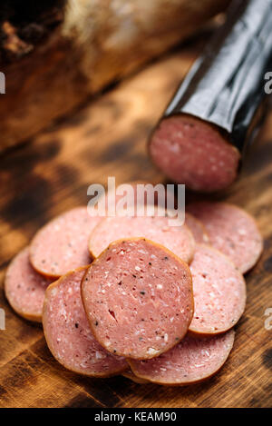Pile of delicious smoked sausage on a burnt wooden cutting board. Stock Photo