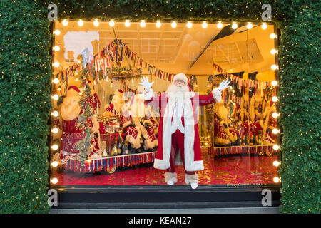 An actor dressed as Father Christmas inside a Christmas window display, themed as With Love From, which is a celebration of the cities Selfridges calls home, at Selfridges department store in Oxford Street, London. Stock Photo