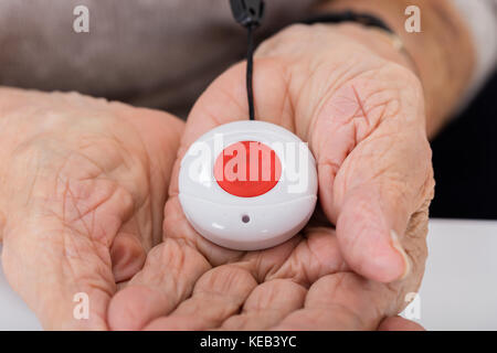 Close-up Of Senior Woman Holding Alarm Button For Emergency Stock Photo