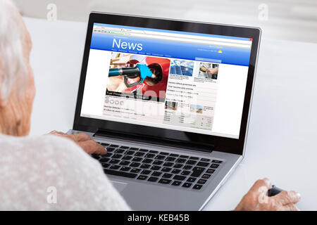 Close-up Of Senior Woman Reading News Online On Laptop At Home Stock Photo
