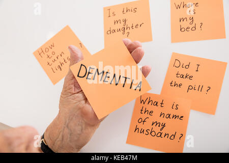 Close-up Of Person's Hand Holding Dementia Sticky Note At Home Stock Photo