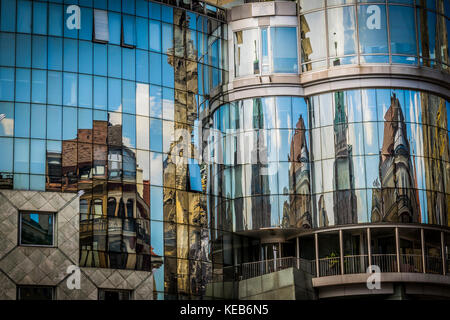 Reflection of houses in glass window of modern building. Modern office building exterior, old houses reflected on the glass of a curtain wall. Stock Photo