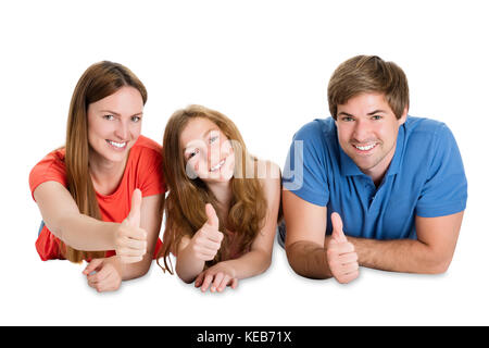 Portrait Of A Happy Couple With Their Daughter Lying Down And Showing Thumb Up Stock Photo