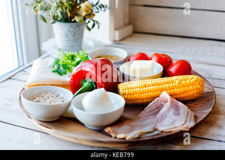 Ingredients for cooking Mexican Quesadilla wrap with vegetables, corn, sweet pepper and sauces on the parchment and table. horizontal view. Stock Photo