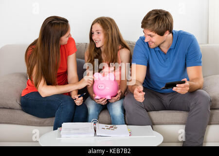 Happy Family Sitting On Sofa Calculating Bills At Home Stock Photo