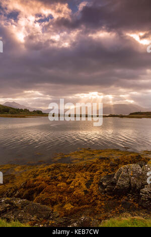 Dramatic dawn light and sunbeams at Ornsay lighthouse on the islet of Eilean Sionnach off the Sleat peninsula, Isle of Skye, Highland, Scotland, UK Stock Photo