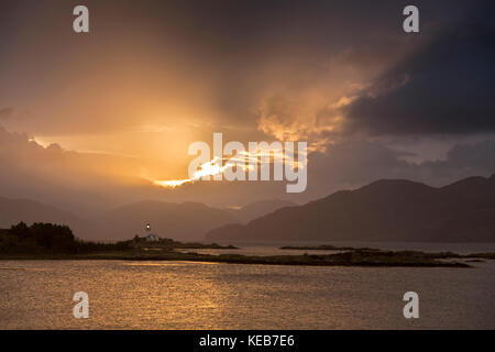 Dramatic dawn light and sunbeams at Ornsay lighthouse on the islet of Eilean Sionnach off the Sleat peninsula, Isle of Skye, Highland, Scotland, UK Stock Photo