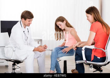 Young Male Neurologist Examining Knee Reflex On Girl In Clinic Stock Photo